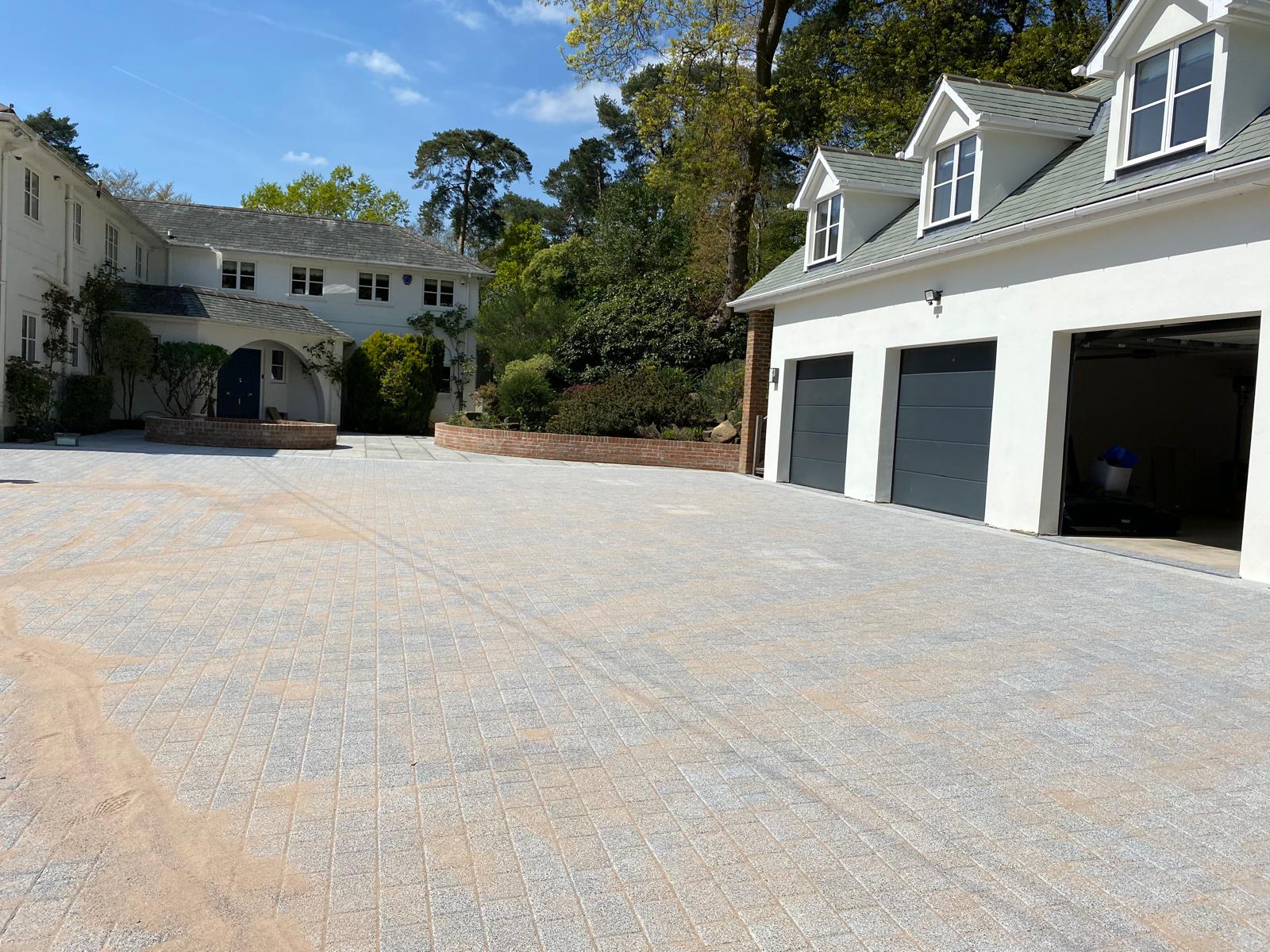 Expansive granite block-paved driveway sweeping around a white country home with triple garage