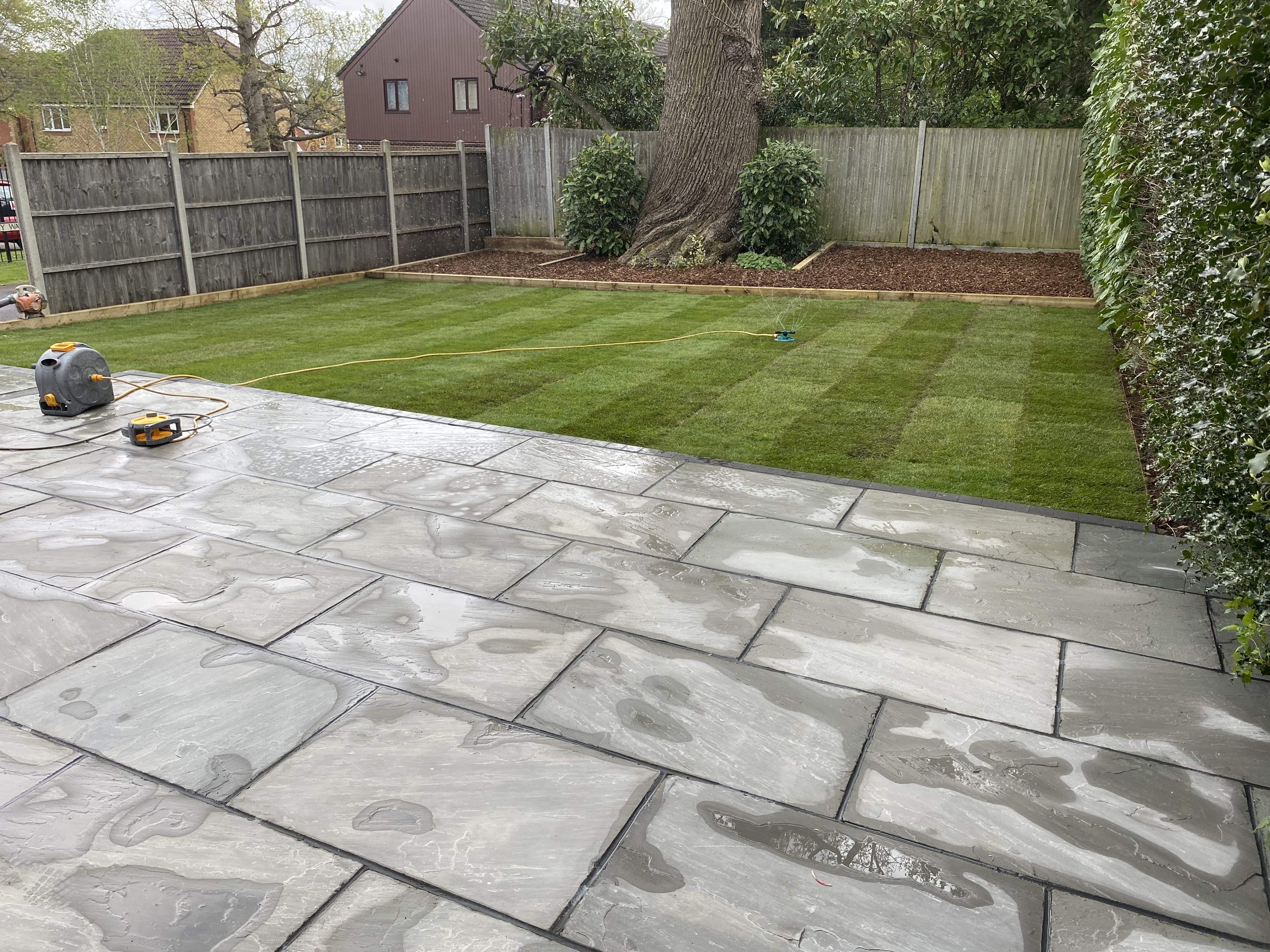 Sandstone patio with brick planter and lawn edging
